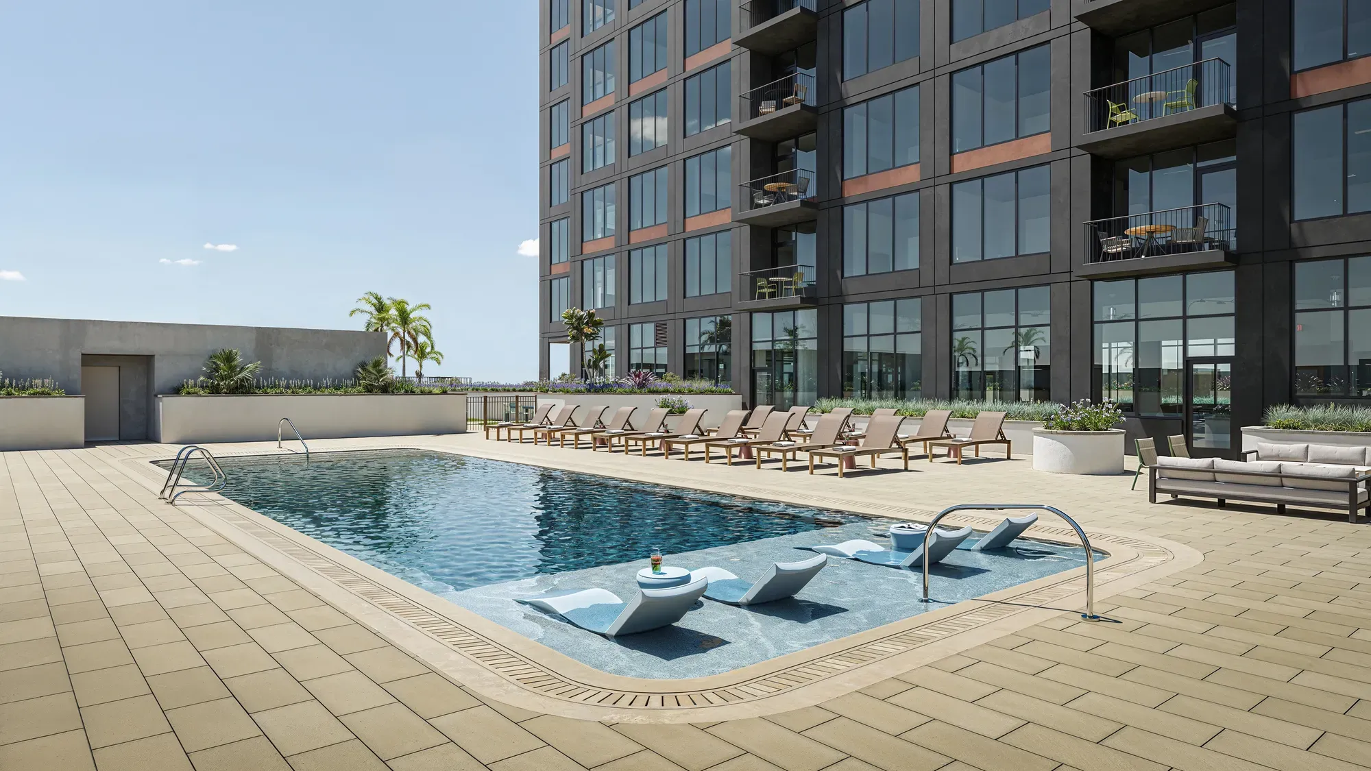 Outdoor swimming pool deck next to a high-rise residential building.