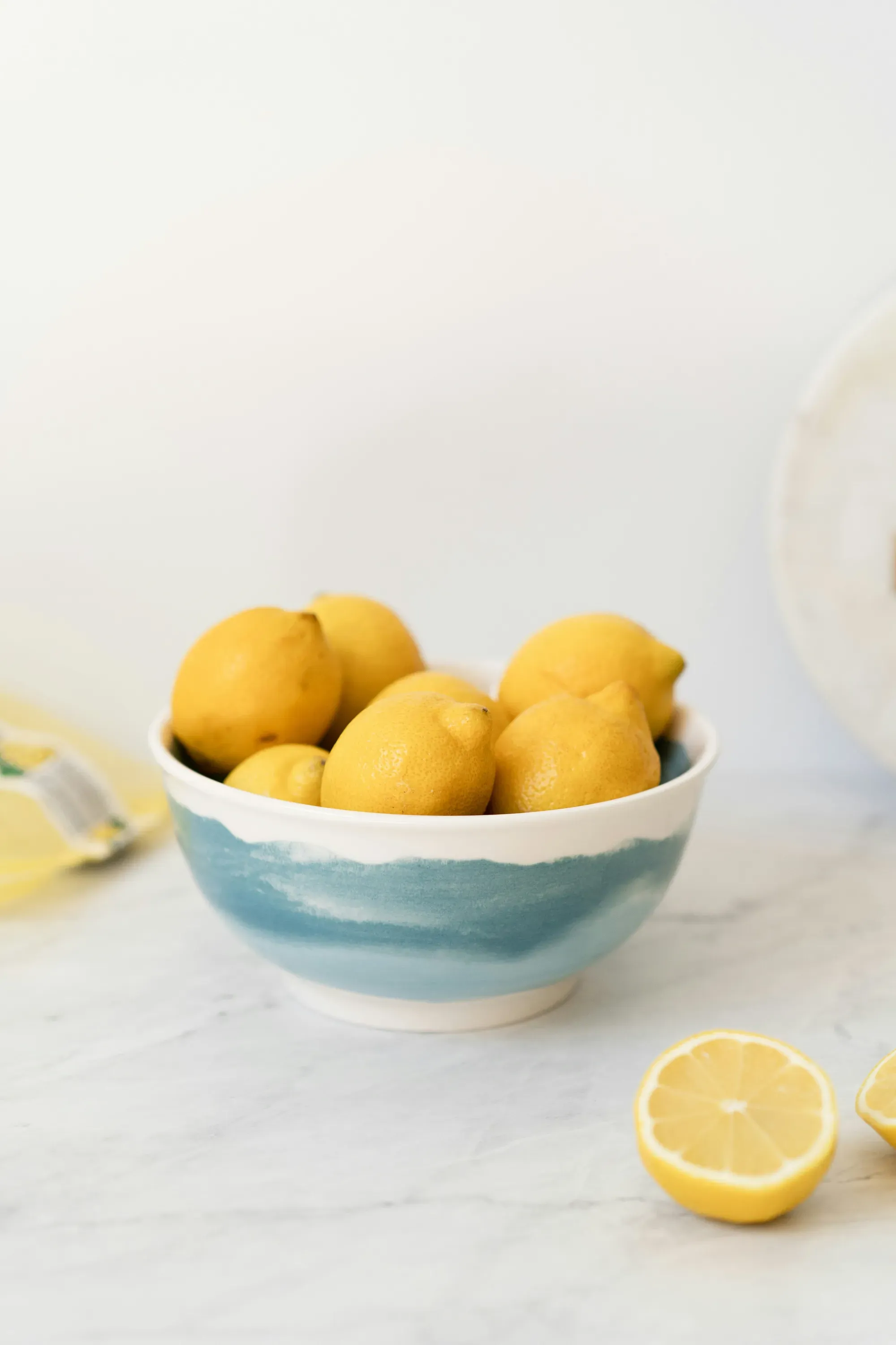 Bowl of lemons on a white table with a lemon half beside it