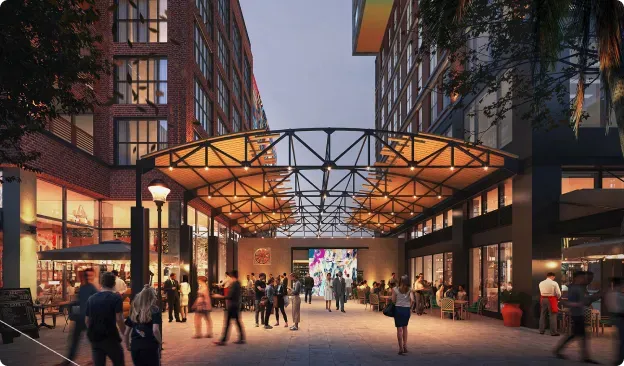 Busy pedestrian plaza and promenade lit up at dusk with overhead geometric canopy lighting.