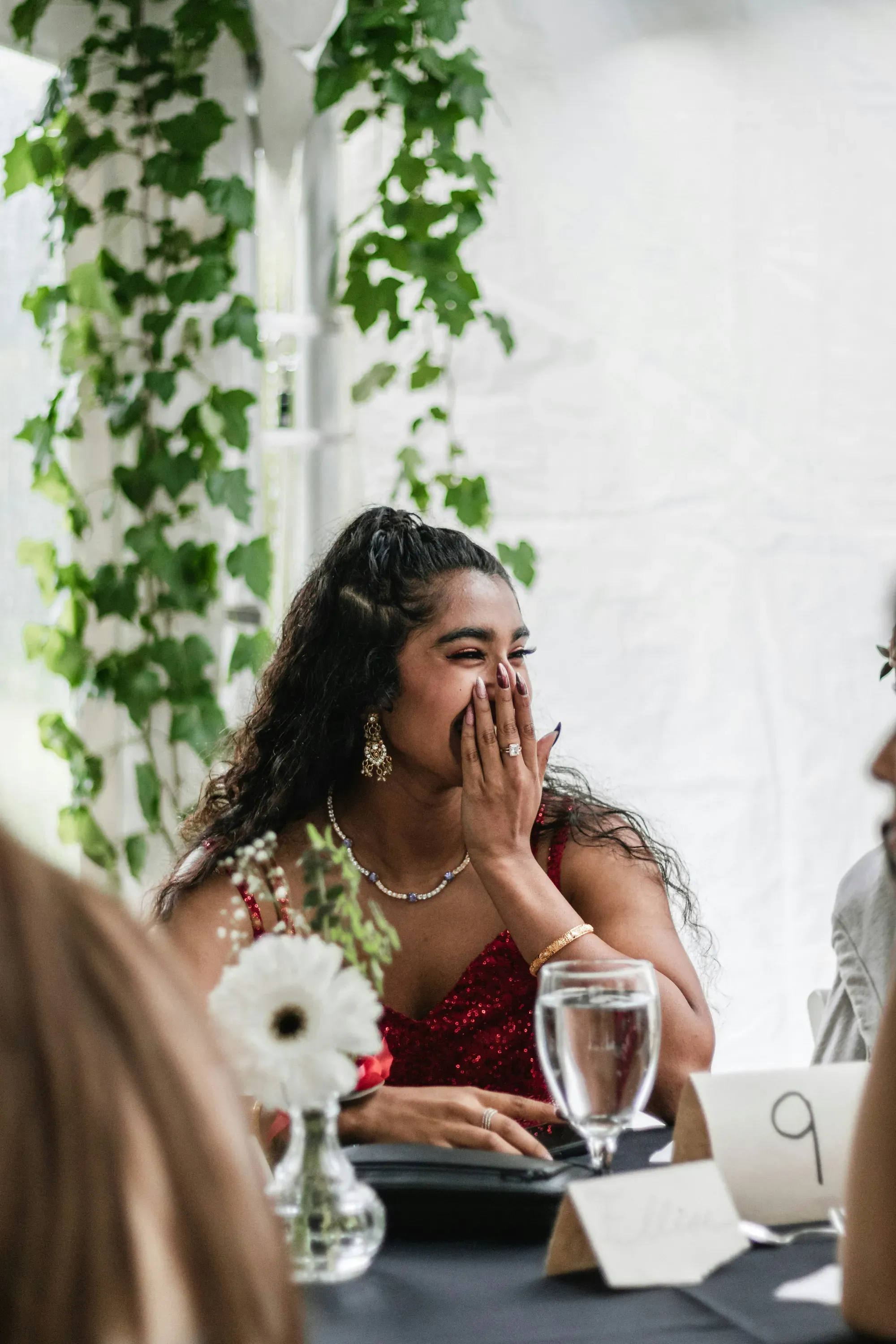 A woman covering her mouth and laughing at a formal event table.