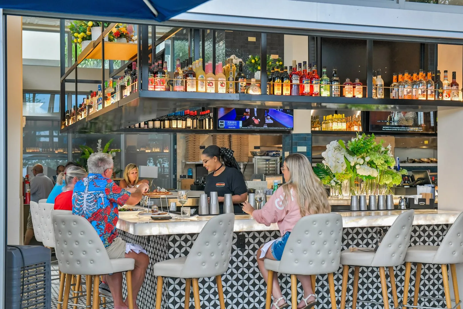 People sitting at a modern indoor bar counter with barstools.