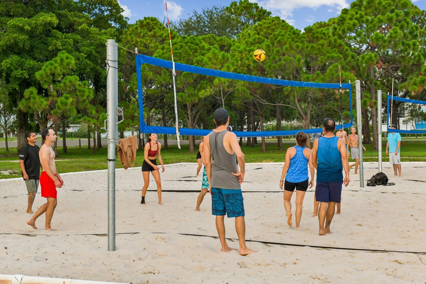 A group of people playing sand volleyball on an outdoor court.